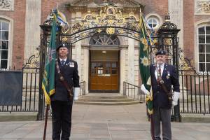Two men in military uniform, bearing standards, stand outside the Worcester Guildhall gates