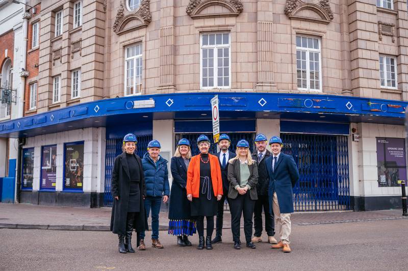 A group of eight people in hard hats, standing in front of the Scala building