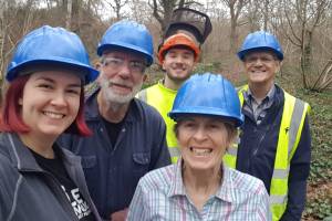 Five people posing in a woodland wearing safety helmets