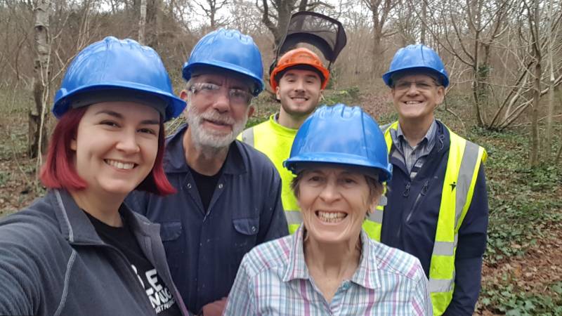 Five people posing in a woodland wearing safety helmets