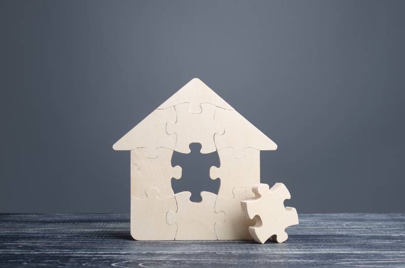 A jigsaw of a house with a piece missing