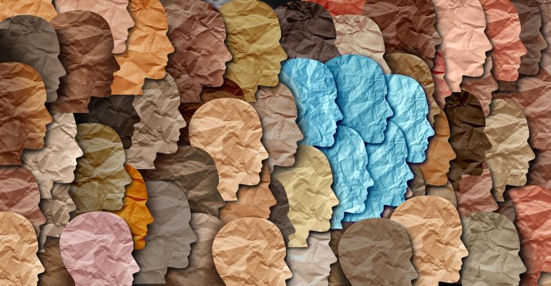 Different coloured sheets of paper, each cut into the shape of a human face