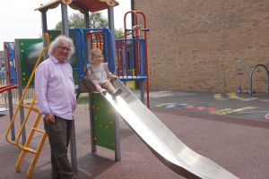 Councillor Adrian Gregson with a little girl trying out the new slide in the Ronkswood toddlers' play area