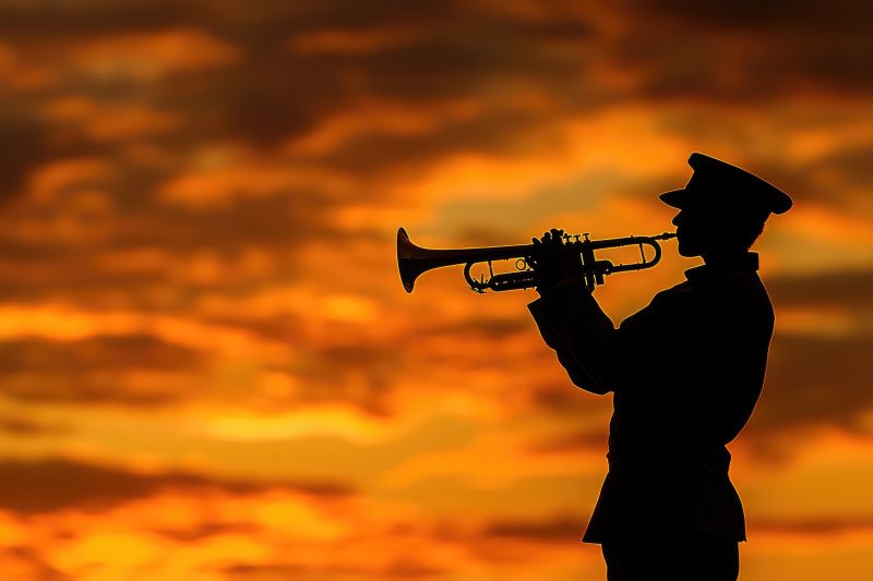 A soldier in uniform playing a trumpet, silhouetted against a sunset
