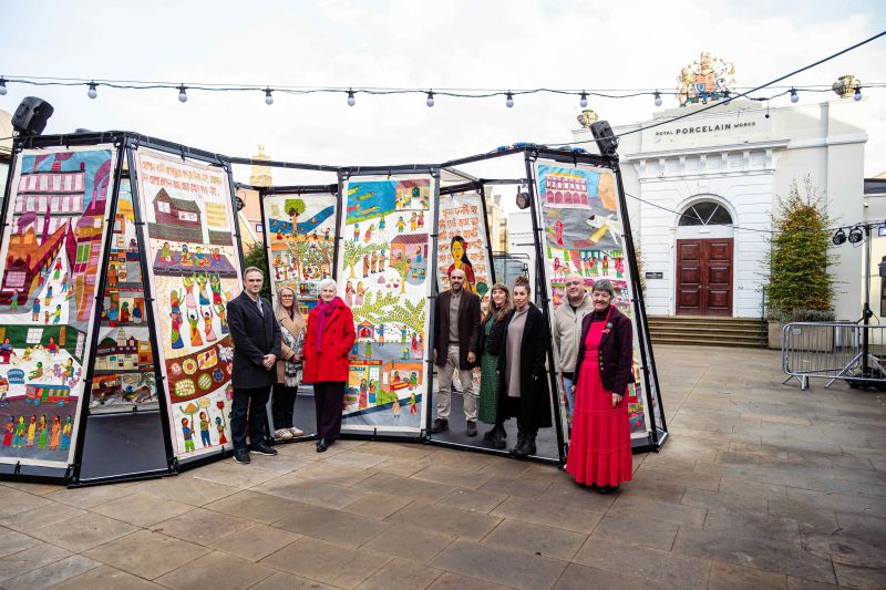 A group of people standing among a display of large tapestries. Photo by Rachel Jones