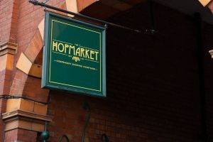 A sign reading "The Hopmarket" hanging up at the entrance to the building