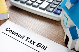 A Council Tax bill lying on a desk, next to a calculator and a model of a house