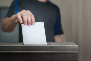 A man posting a voting slip into a ballot box