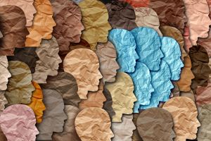 Different coloured sheets of paper, each cut into the shape of a human face
