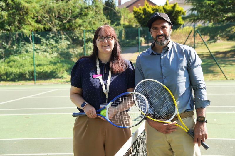 A man and a woman stood holding tennis rackets