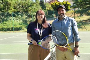 A man and a woman stood holding tennis rackets