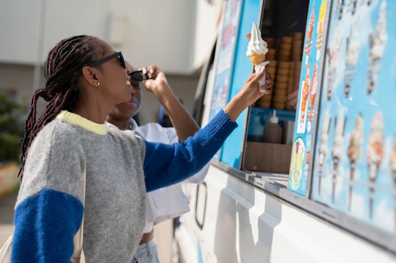 A person with an ice cream next to an ice cream van