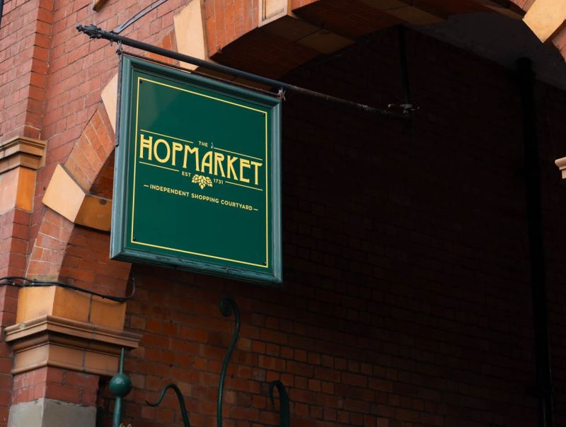 A sign reading "The Hopmarket" hanging up at the entrance to the building