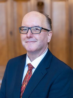 A man in a suit and tie, wearing glasses