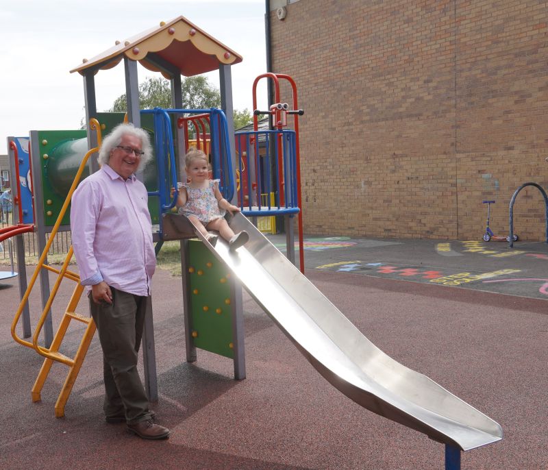 Councillor Adrian Gregson with a little girl trying out the new slide in the Ronkswood toddlers' play area